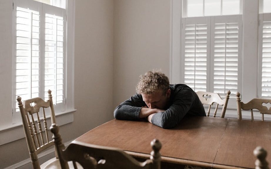 Man in Gray Long Sleeve Shirt Sitting on Brown Wooden Chair