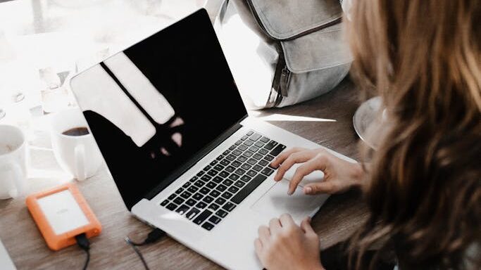 Close-up Photography of Woman Sitting Beside Table While Using Macbook