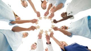 Directly below shot of medical team joining jigsaw pieces in huddle against white background