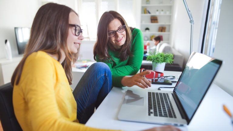 Photo of mother with daughter doing homework on the lap top.