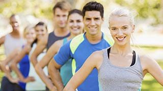 Portrait of beautiful fit woman with friends standing in a row at park.