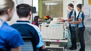 Two students evaluating a patient in a simulated hospital room